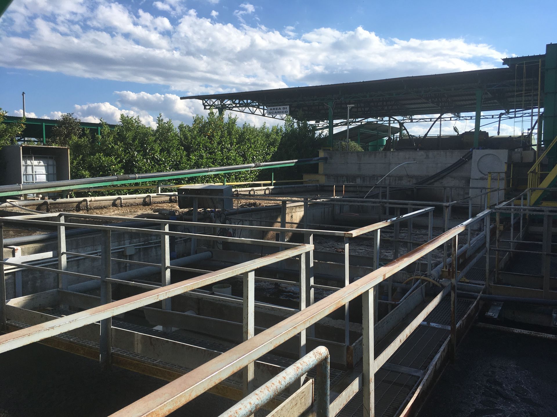 Impianto di trattamento delle acque reflue industriali con passerelle metalliche e serbatoi sotto una struttura coperta.