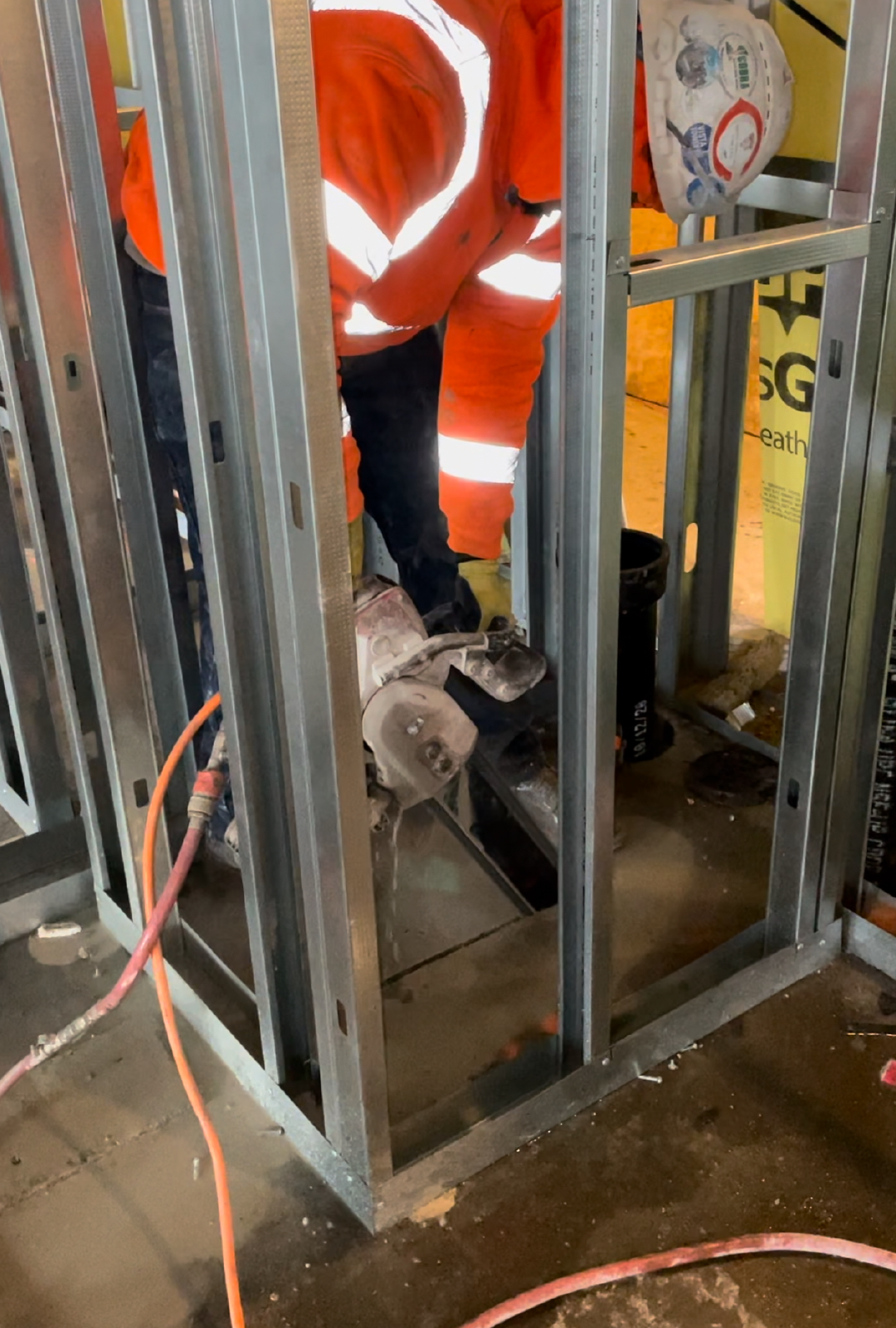 A construction worker is cutting a concrete floor with a handheld concrete saw