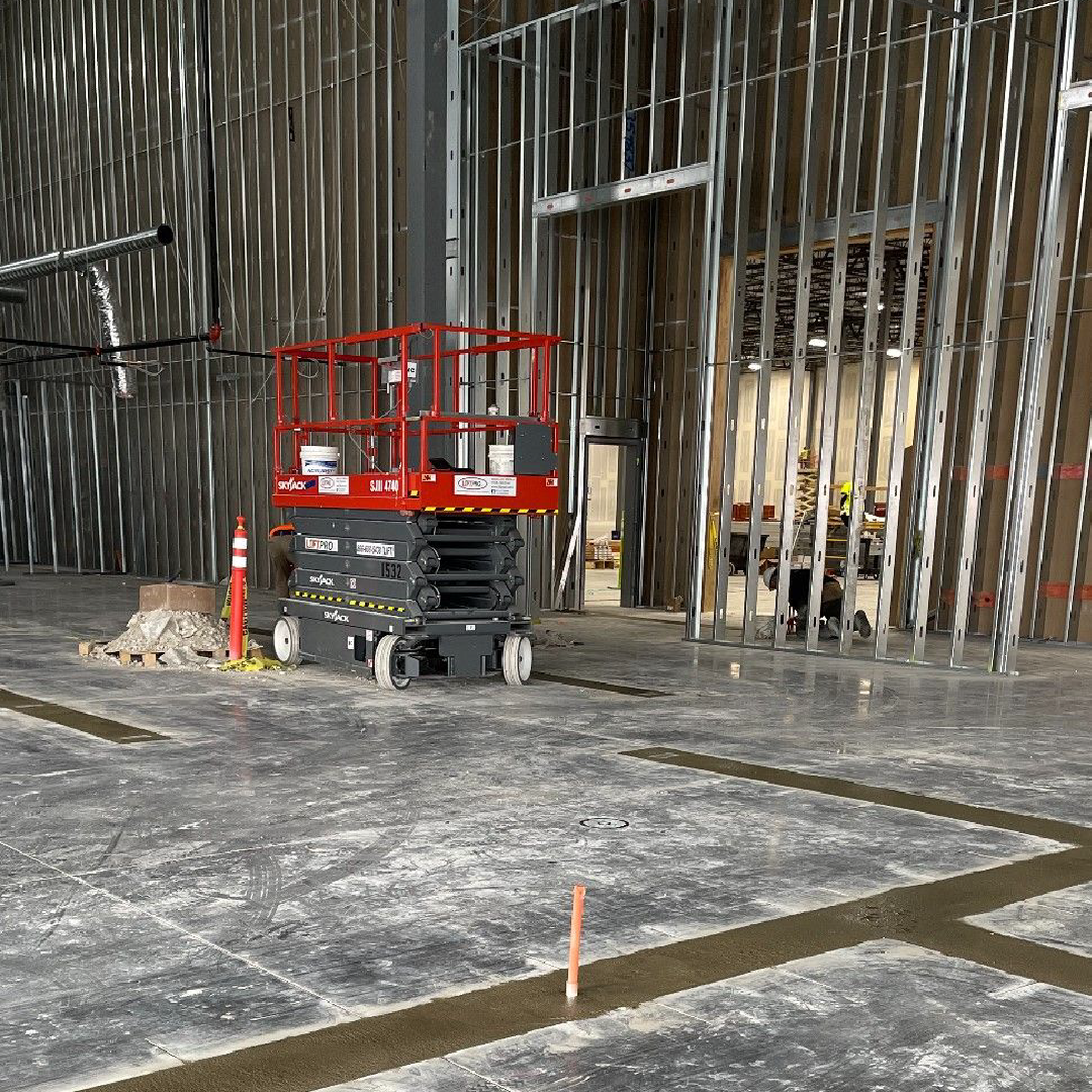 A scissor lift is sitting in the middle of a building under construction.