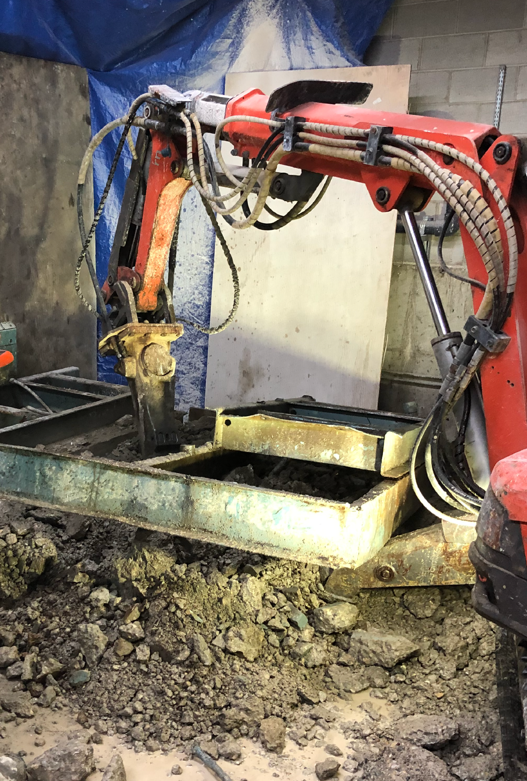 A red concrete breaking robot is sitting on top of a pile of dirt.