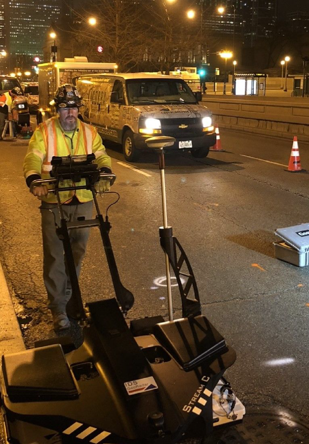 A man is standing next to a machine on the side of the road.