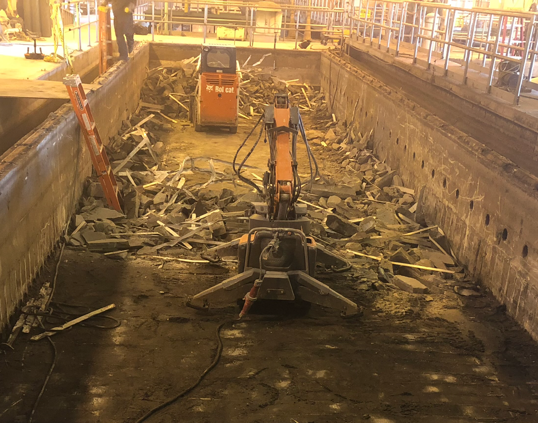 A machine is breaking up concrete while another one is hauling it away.