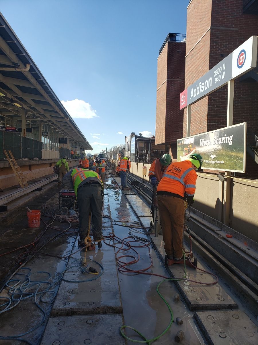 A group of construction workers are working on a train track.