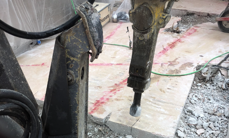 a concrete demolition robot in action smashing concrete while the operator is at a safe distance