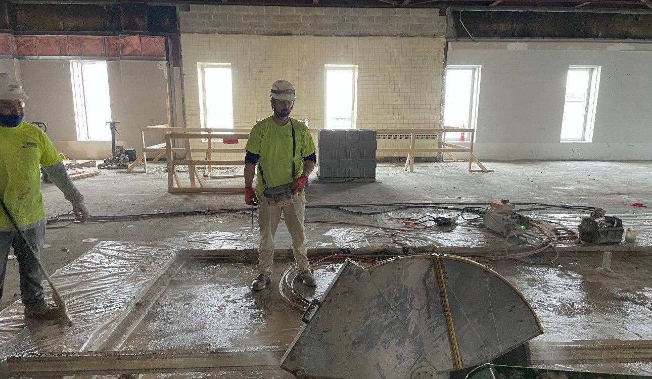 Two construction workers are standing in a large room.