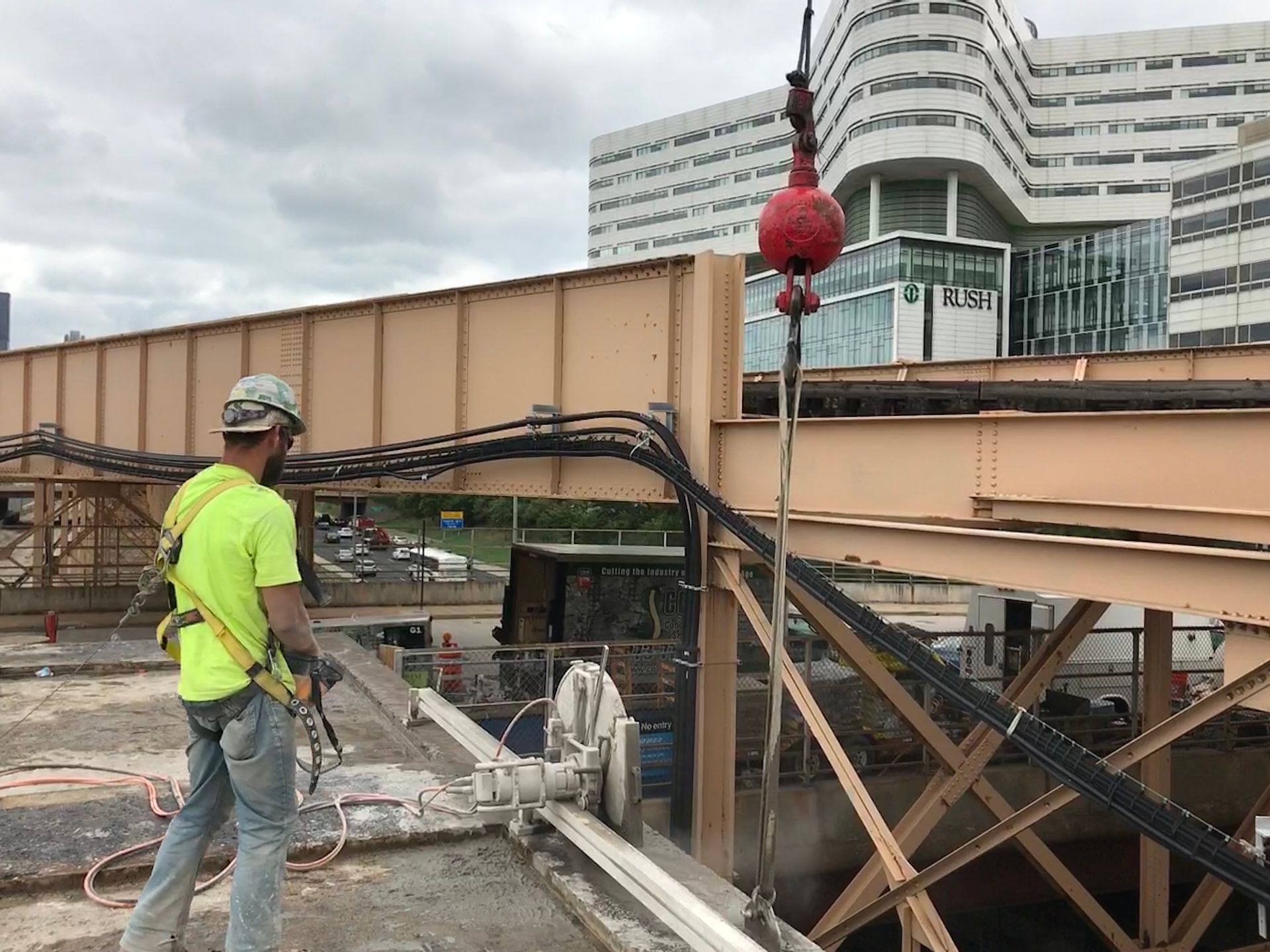 A construction worker is cutting concrete on a bridge with a wall saw