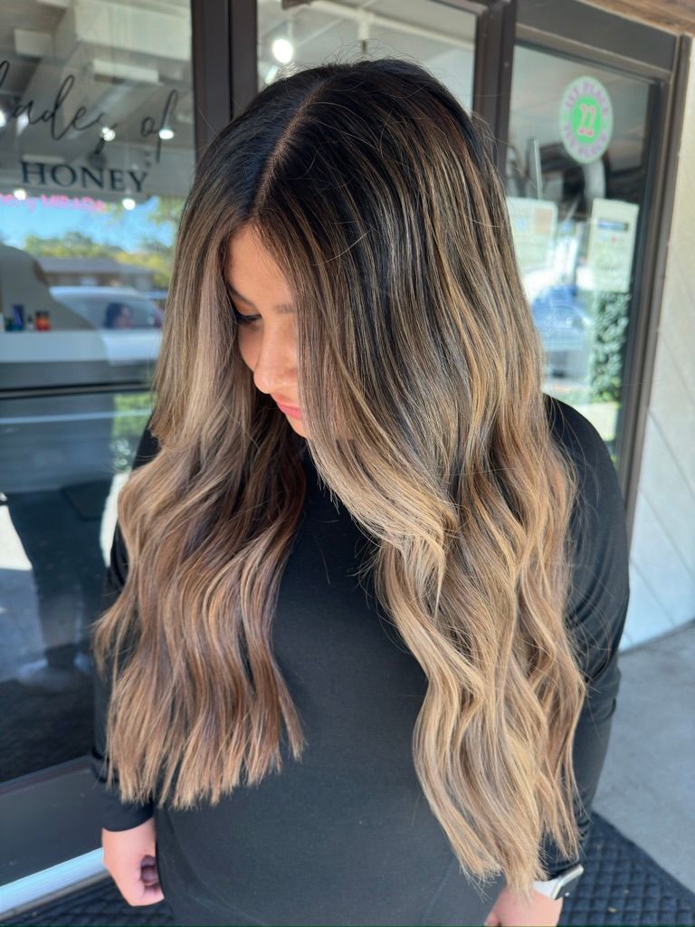 A woman with long brown hair is standing in front of a store.
