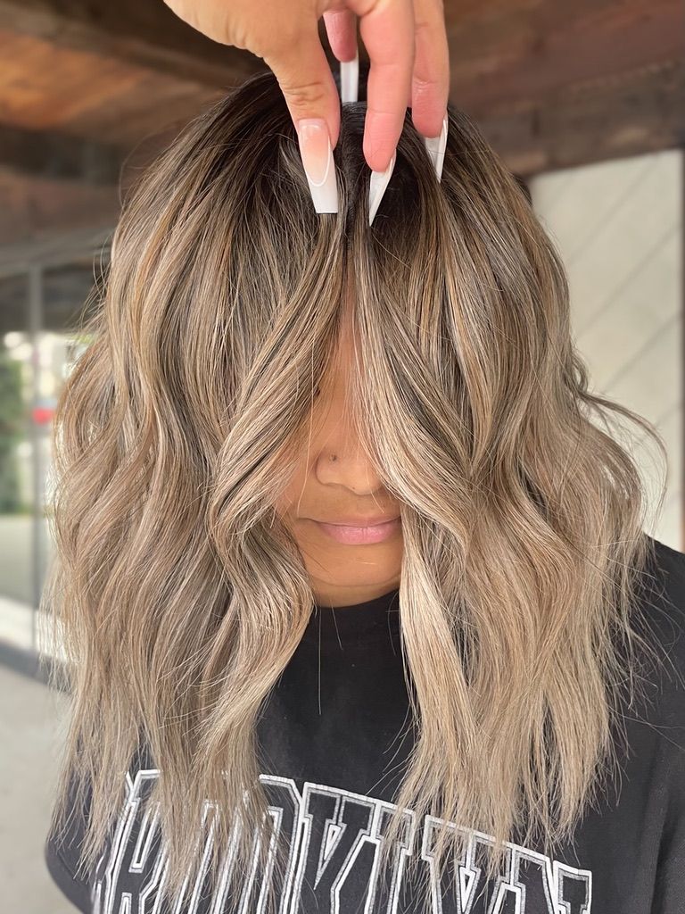 A woman with long nails is covering her face with her hair.