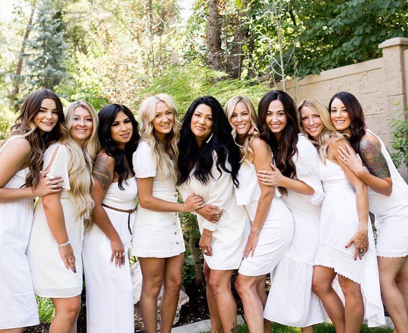 A group of women in white dresses are posing for a picture.