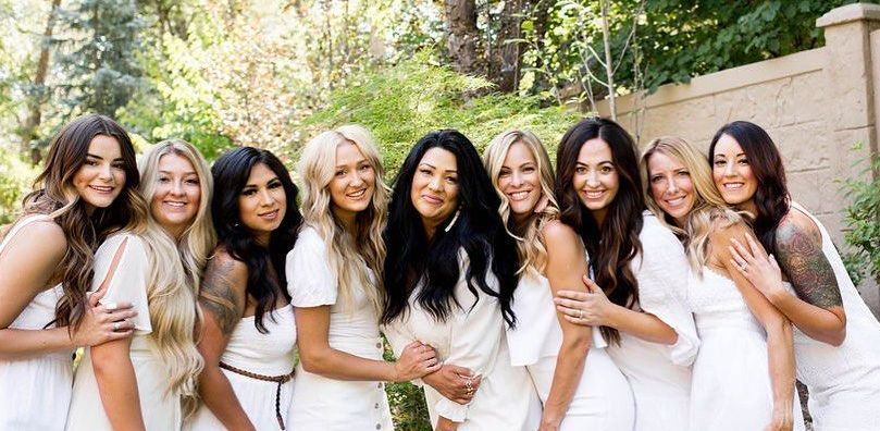 A group of women in white dresses are posing for a picture.