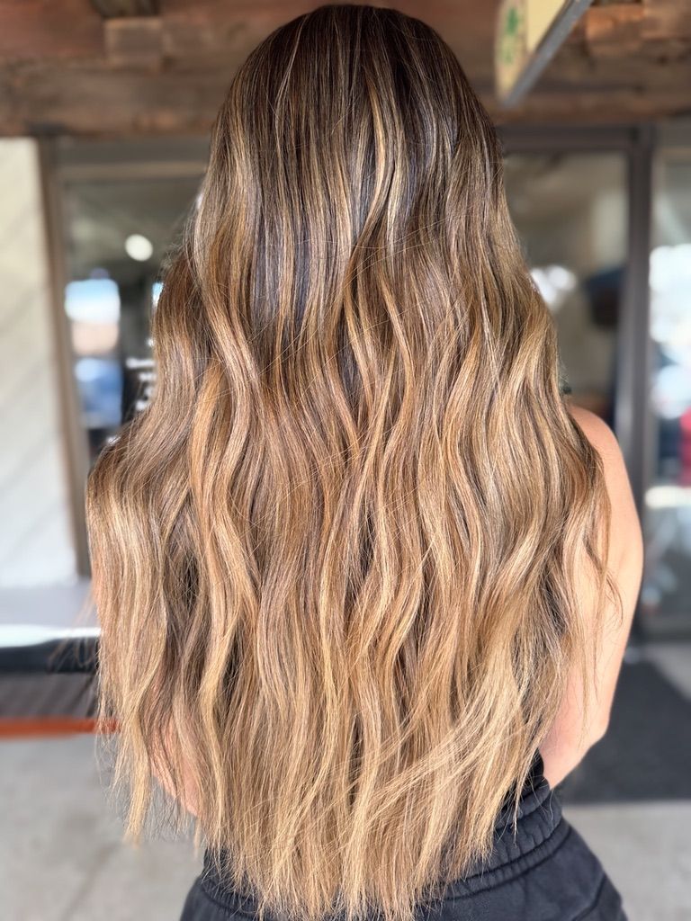 A woman with long brown hair is standing in front of a building.