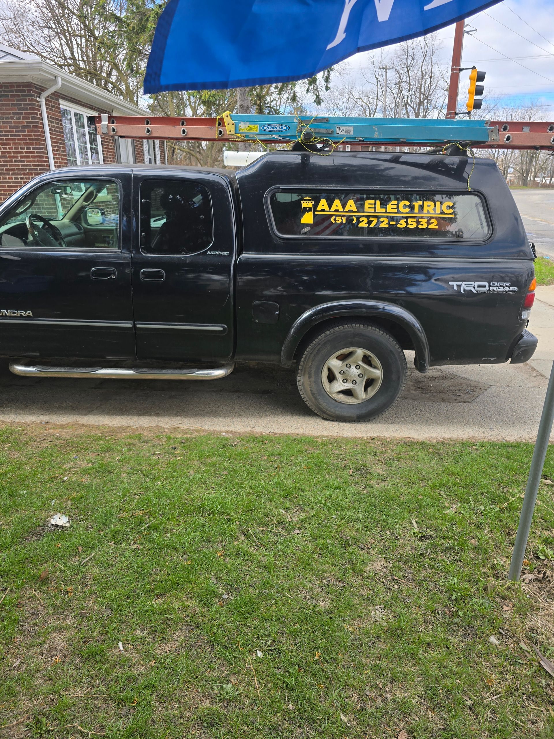 A black truck with a canopy on top of it is parked on the side of the road.