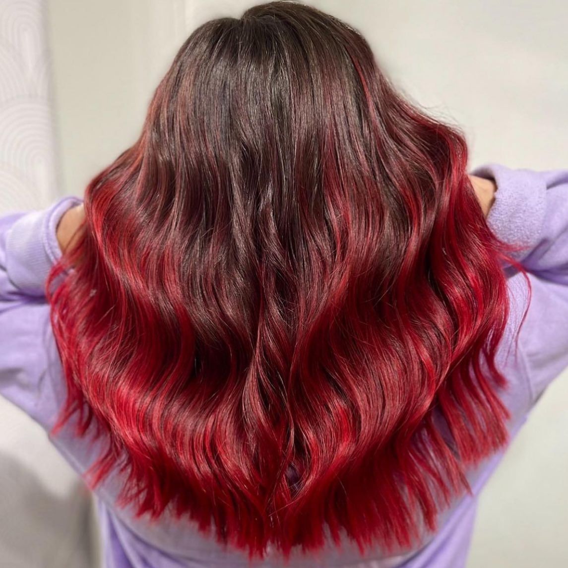 A woman with red hair is wearing a purple sweater.