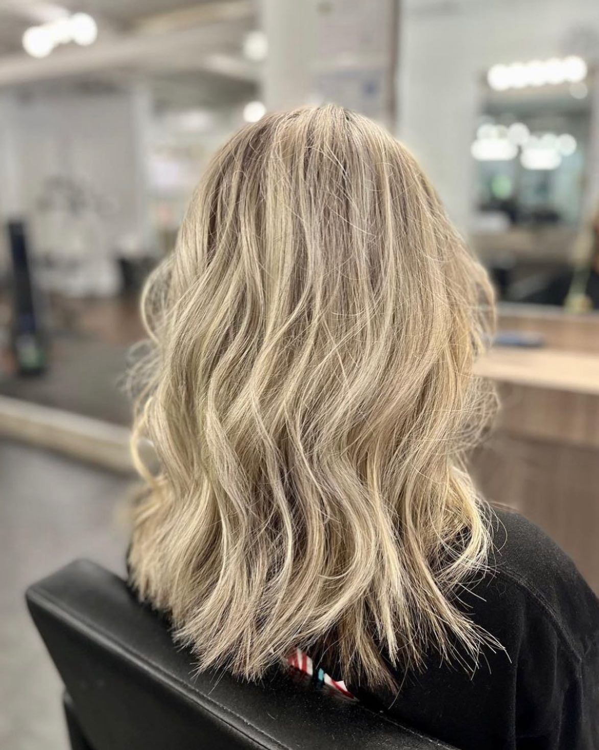A woman with blonde hair is sitting in a chair in a salon.