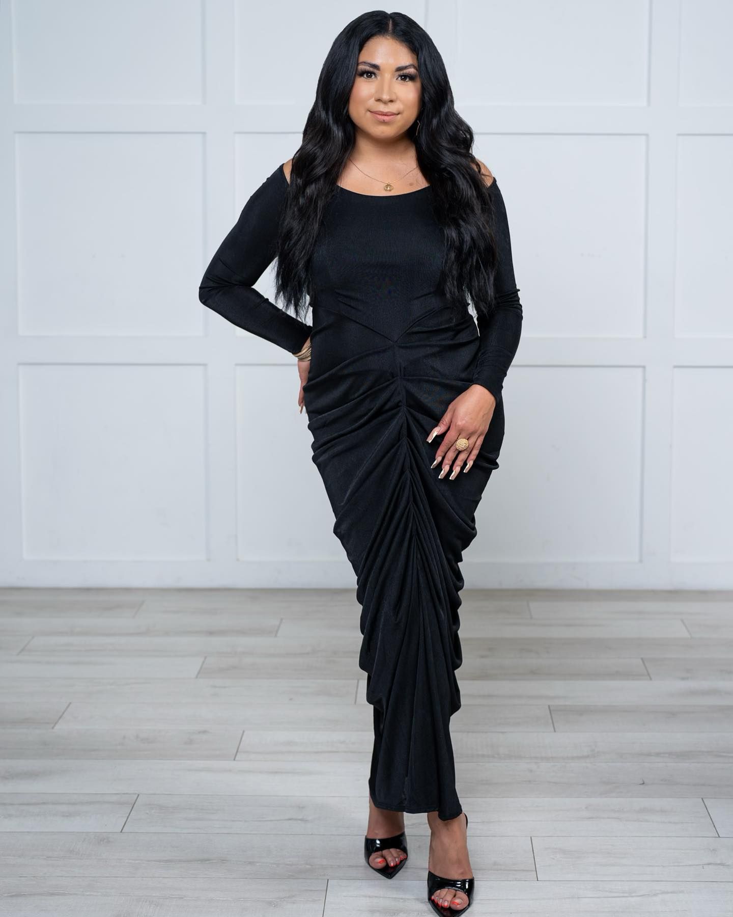 A woman in a black dress is standing on a wooden floor.