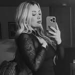 A woman is taking a selfie with her phone in a black and white photo.