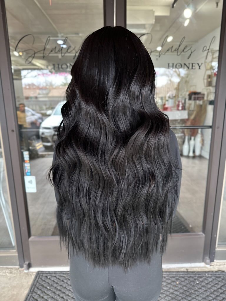 A woman with long black hair is standing in front of a door.