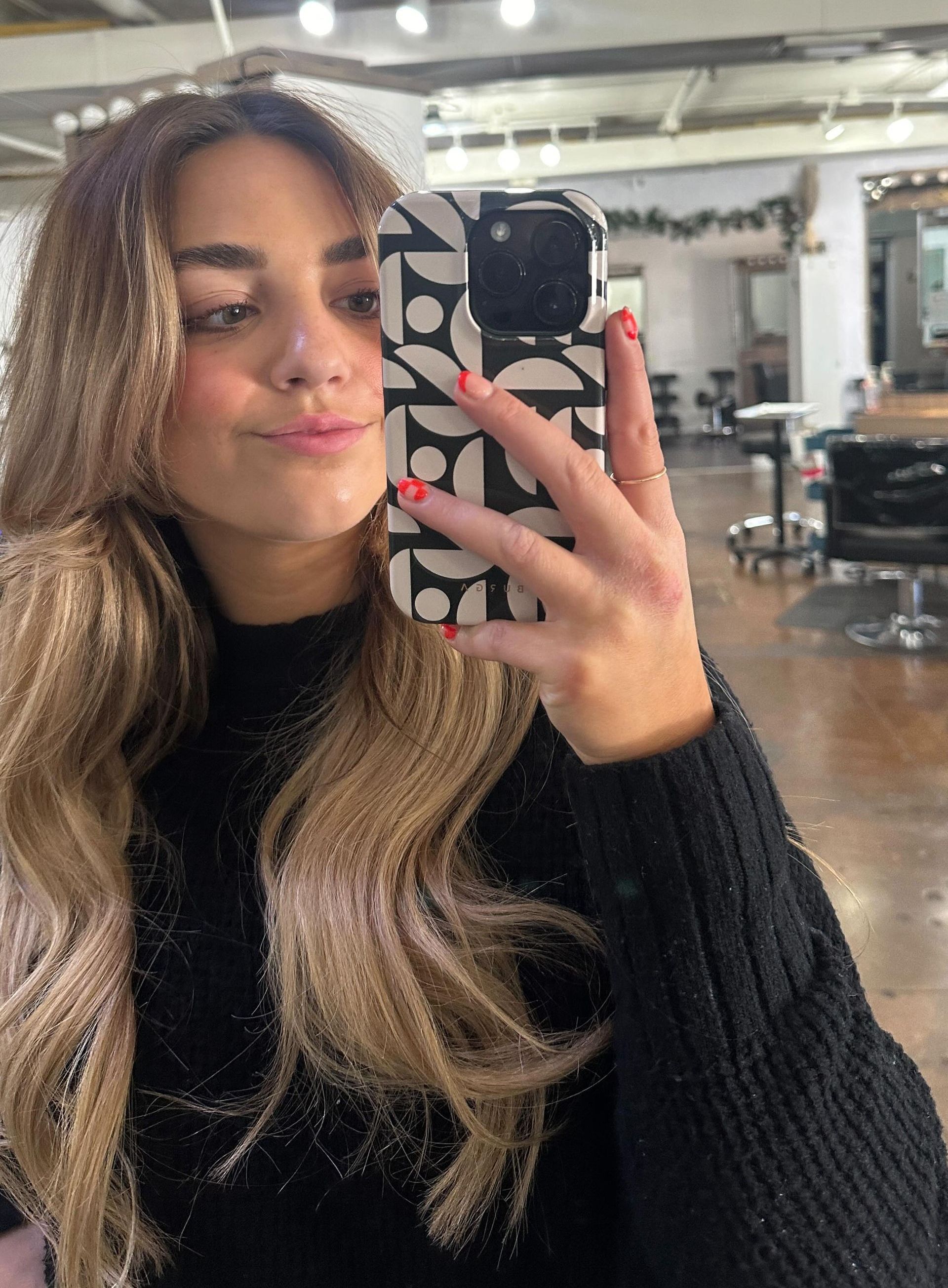 A woman is taking a selfie with her phone in a salon.