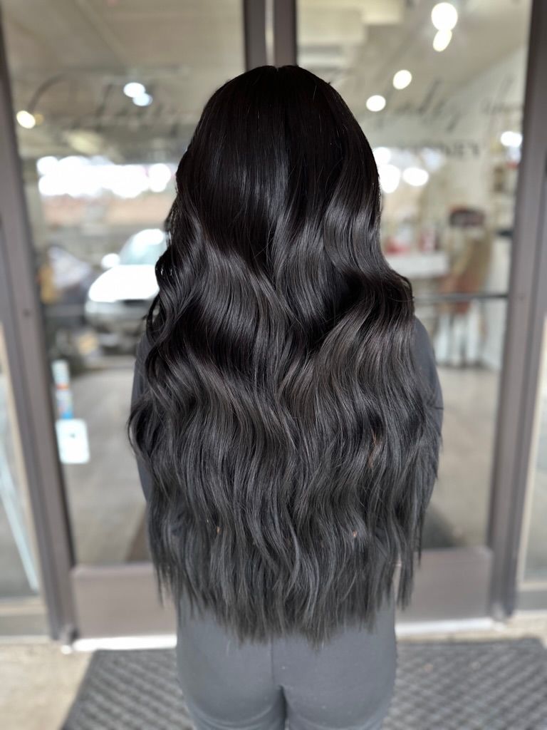 A woman with long black hair is standing in front of a glass door.