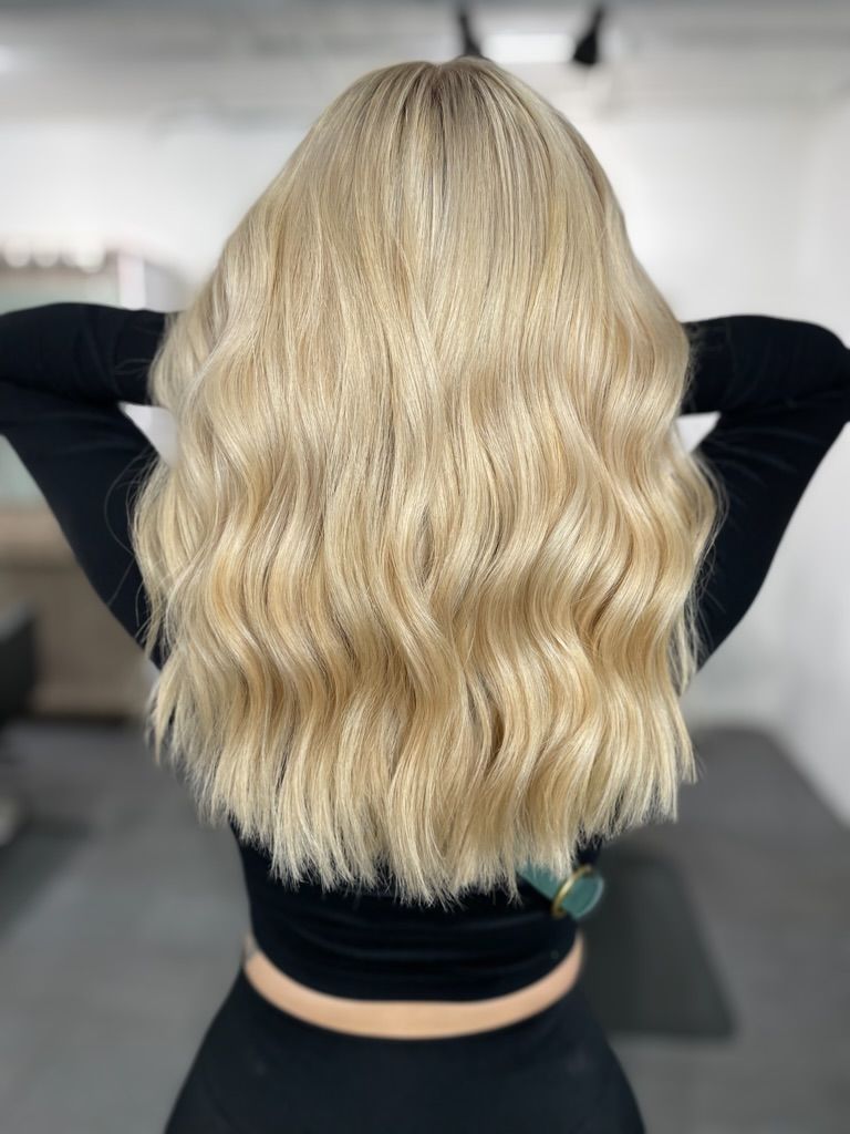 A woman with blonde wavy hair is wearing a black top.