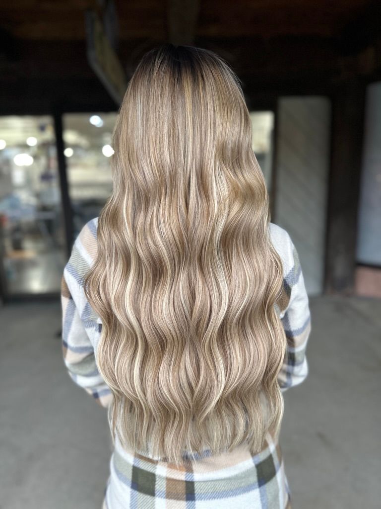 A woman with long blonde hair is wearing a plaid shirt.