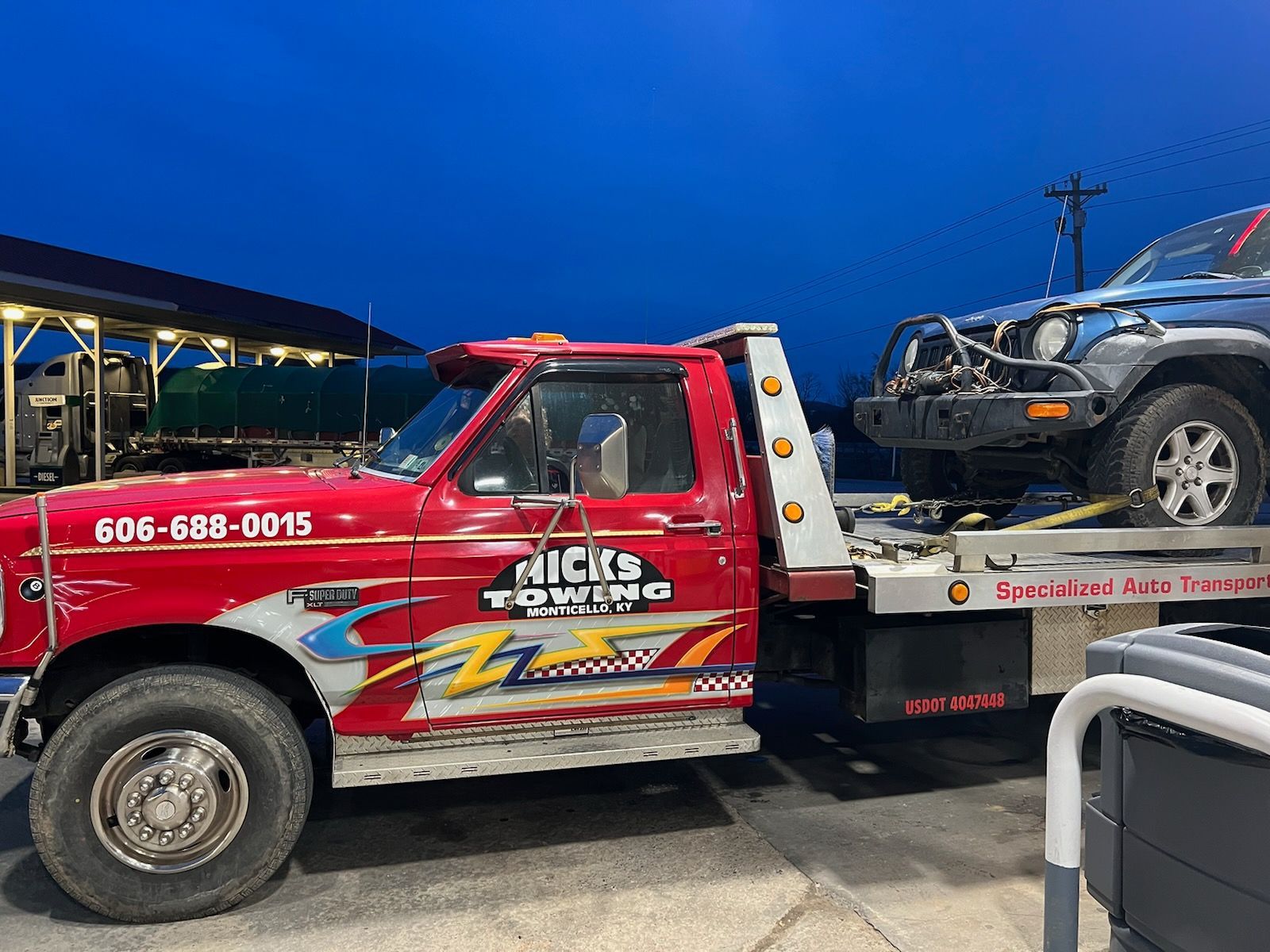 A red tow truck is carrying a jeep on the back of it.