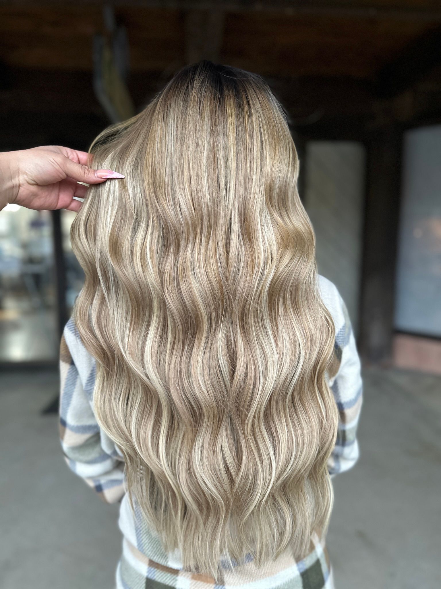A woman with long blonde hair is getting her hair done by a hairdresser.