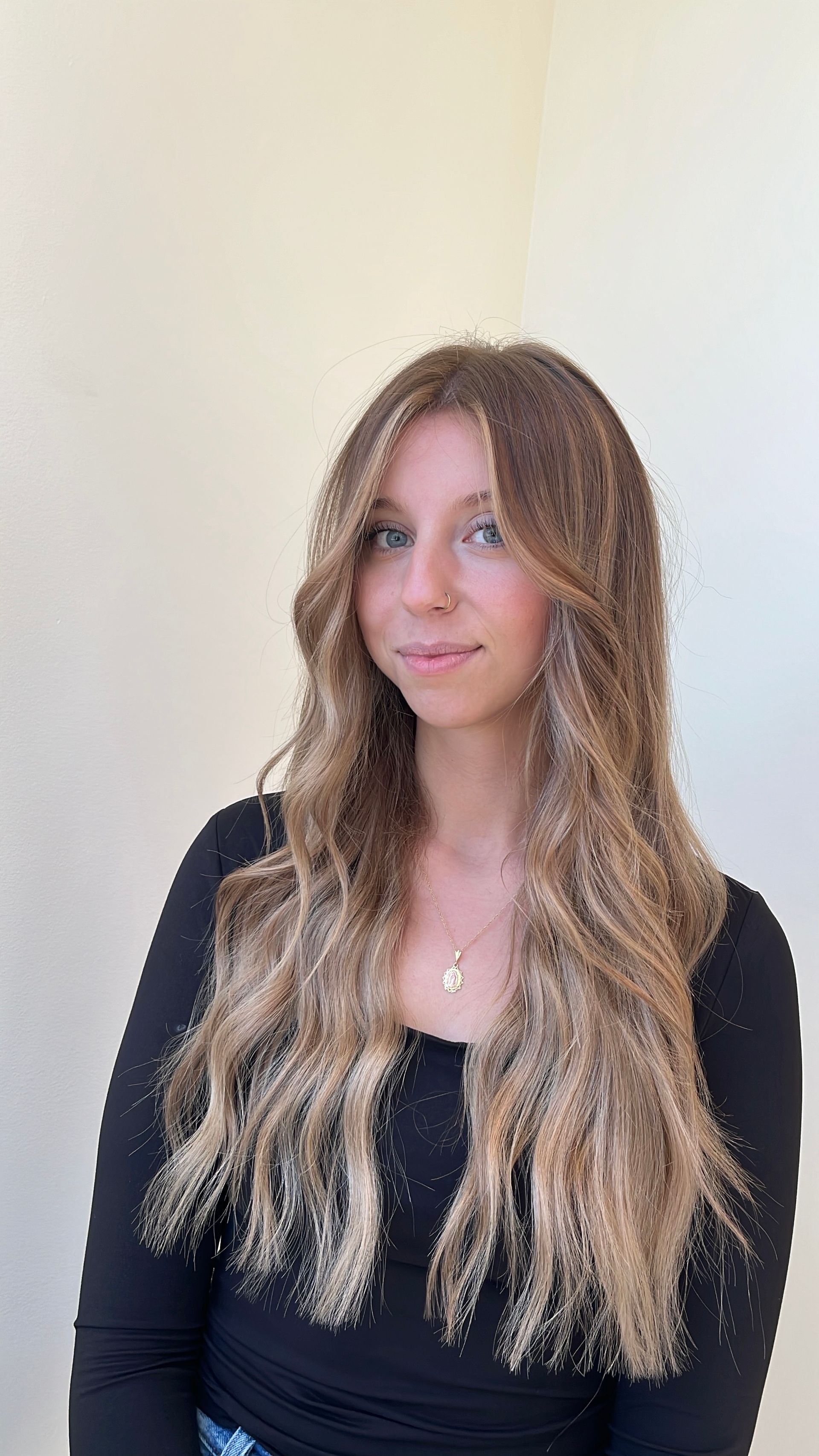 A woman with long hair is wearing a black shirt and a necklace.