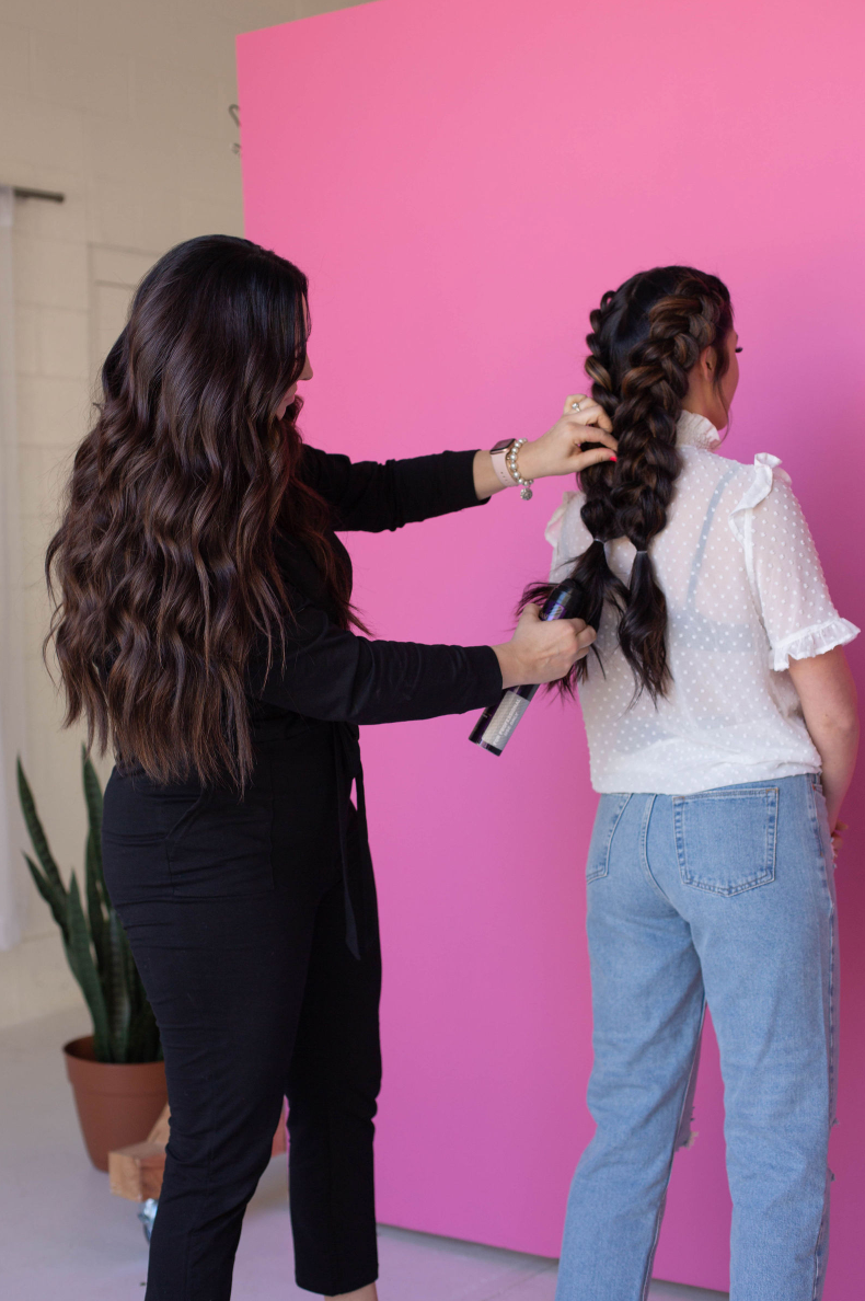 A woman is getting her hair extensions done at a salon.
