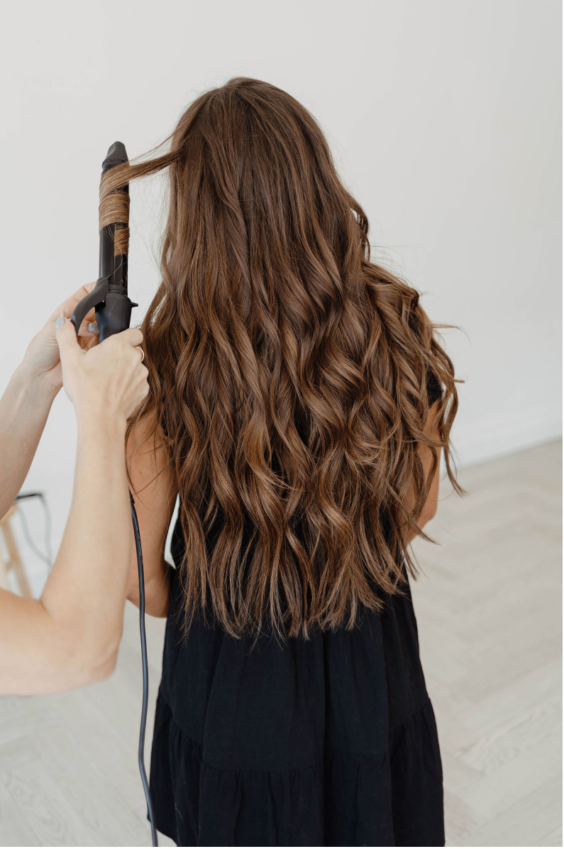 A woman is getting her hair straightened by a hairdresser in a salon.
