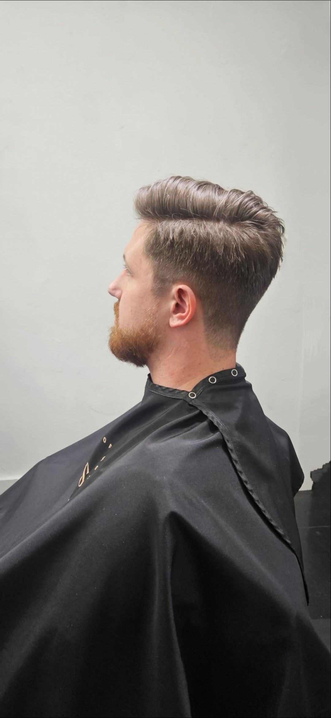A man is getting his hair cut at a barber shop.
