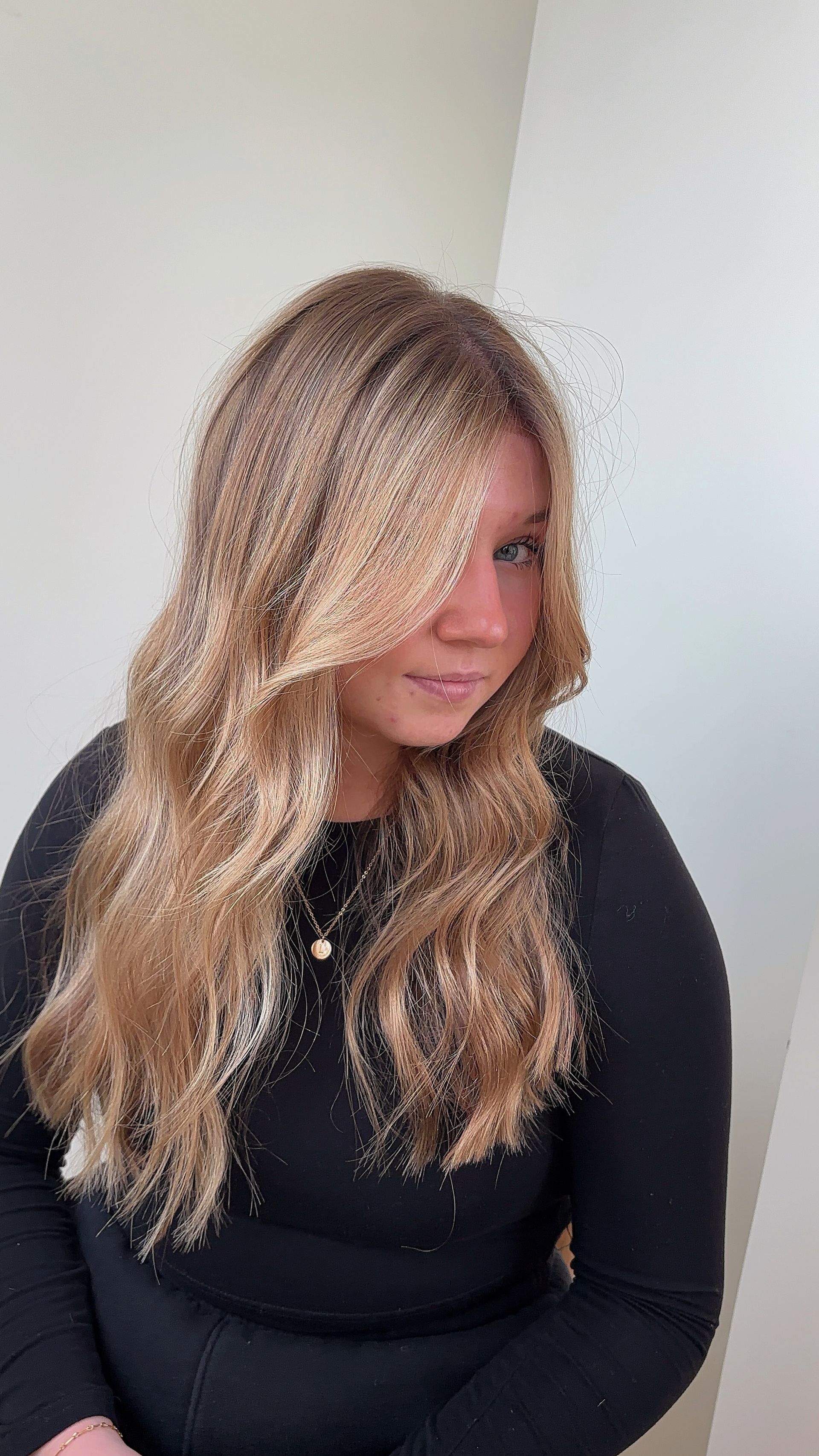 A woman with long blonde hair is wearing a black shirt.