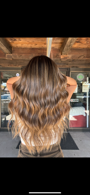 A woman with long brown hair is standing in front of a building.
