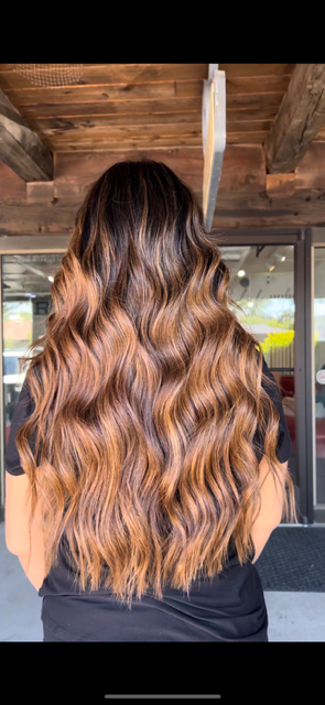 A woman with long brown hair is standing in front of a wooden ceiling.
