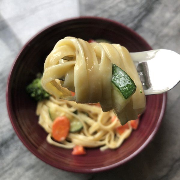vegan pasta Alfredo primavera close up on fork