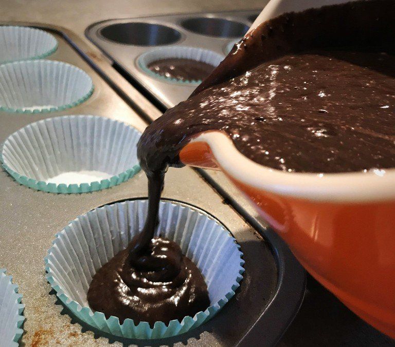 cake batter being poured in cupcake papers