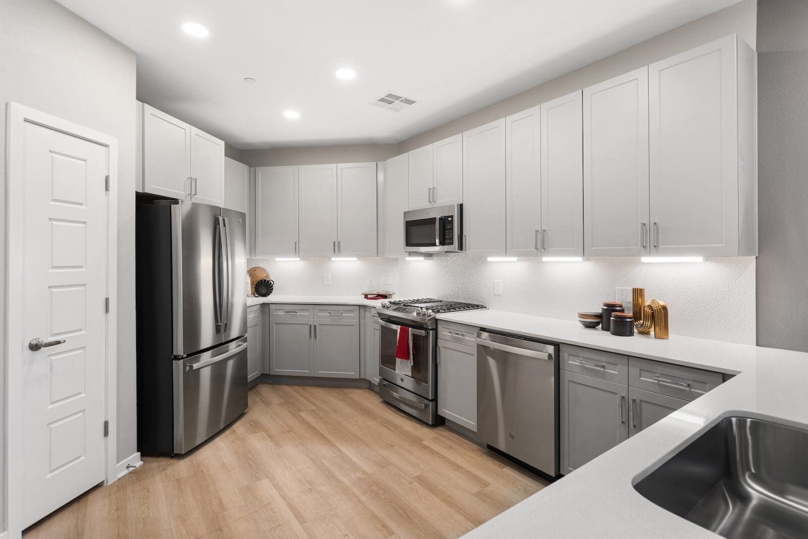 Modern kitchen with light gray cabinets, stainless steel appliances, and wood-look flooring at Echo Biltmore in Phoenix, AZ..