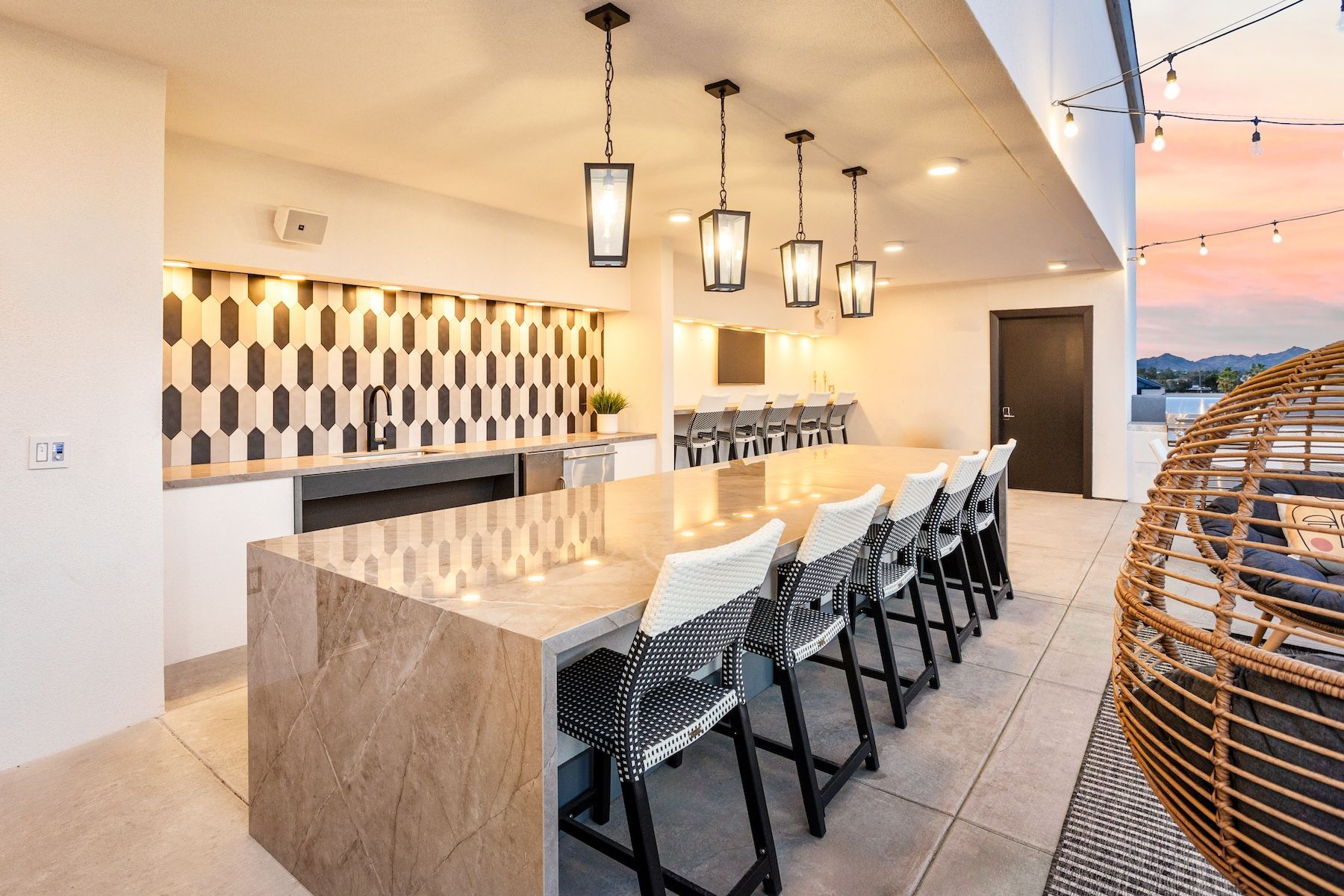 Rooftop outdoor kitchen with a long bar, seating, and overhead lighting at Echo Biltmore in Phoenix, AZ..