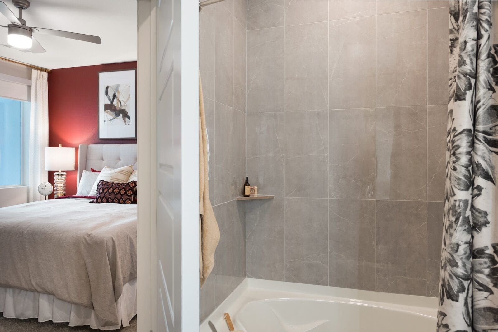 Bathroom with tiled walls and a peek into a bedroom with a bed and red wall at Echo Biltmore in Phoenix, AZ..