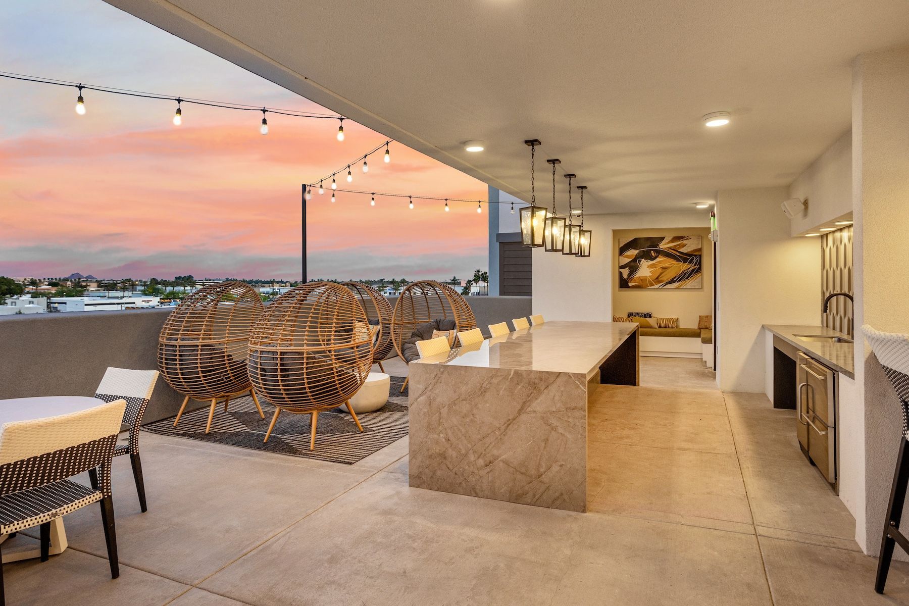 Rooftop patio at sunset with seating, bar, string lights, and city views at Echo Biltmore in Phoenix, AZ..