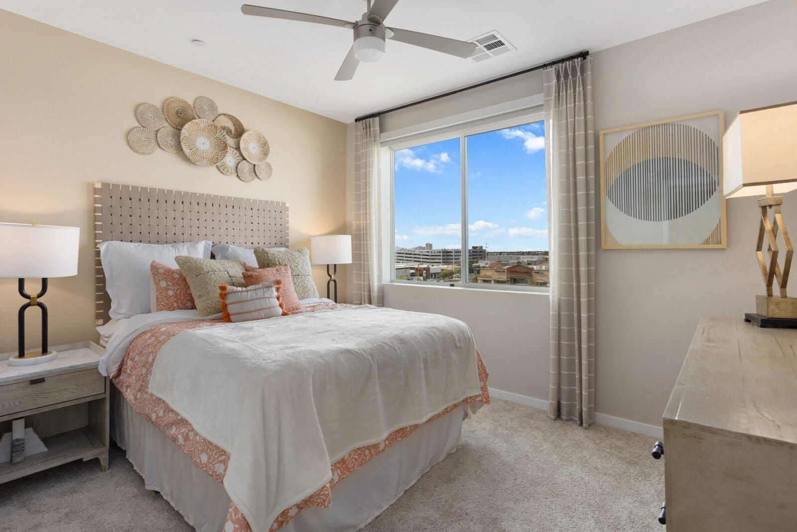 Bedroom with a bed, nightstands, artwork, and a window with a city view at Echo Biltmore in Phoenix, AZ..