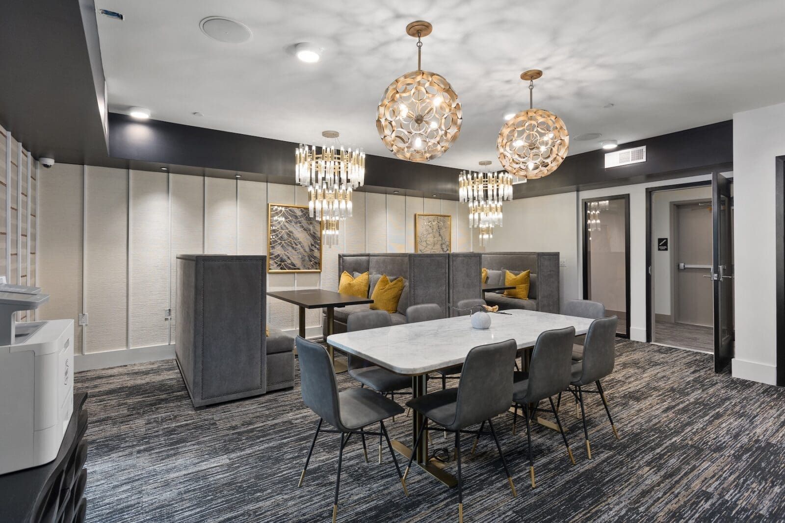 Modern dining area with gray booth seating, marble table, and crystal chandeliers at Echo Biltmore in Phoenix, AZ..