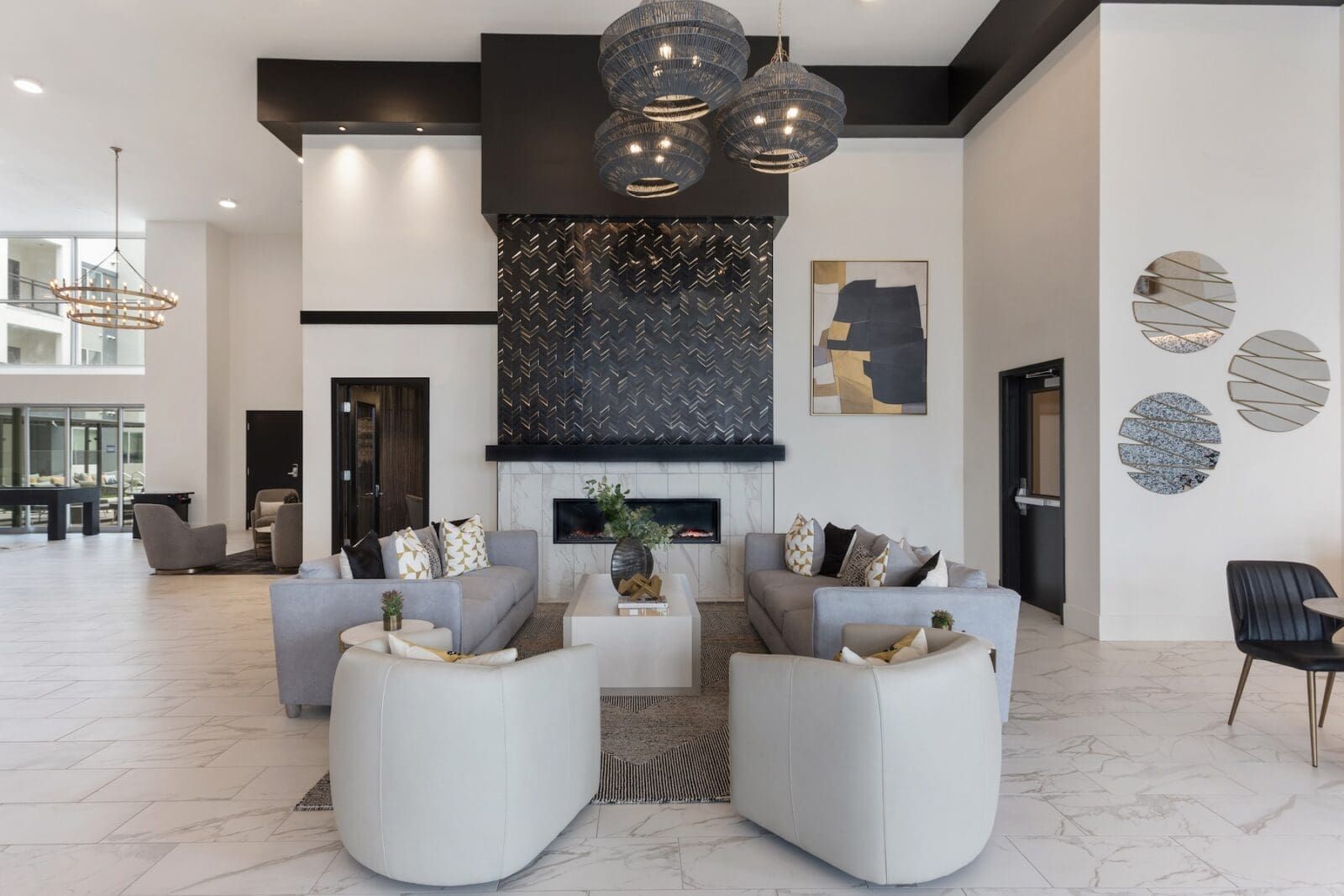 Spacious lobby with gray couches, fireplace, decorative lighting, and artwork at Echo Biltmore in Phoenix, AZ..