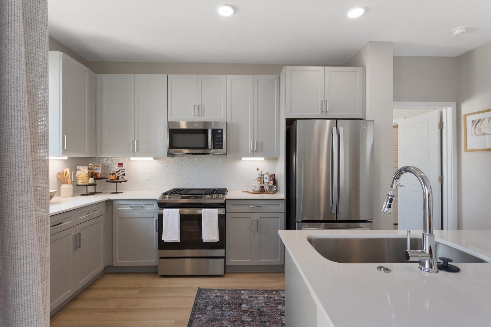 Modern kitchen with light gray cabinets, stainless steel appliances, and white countertops at Echo Biltmore in Phoenix, AZ..