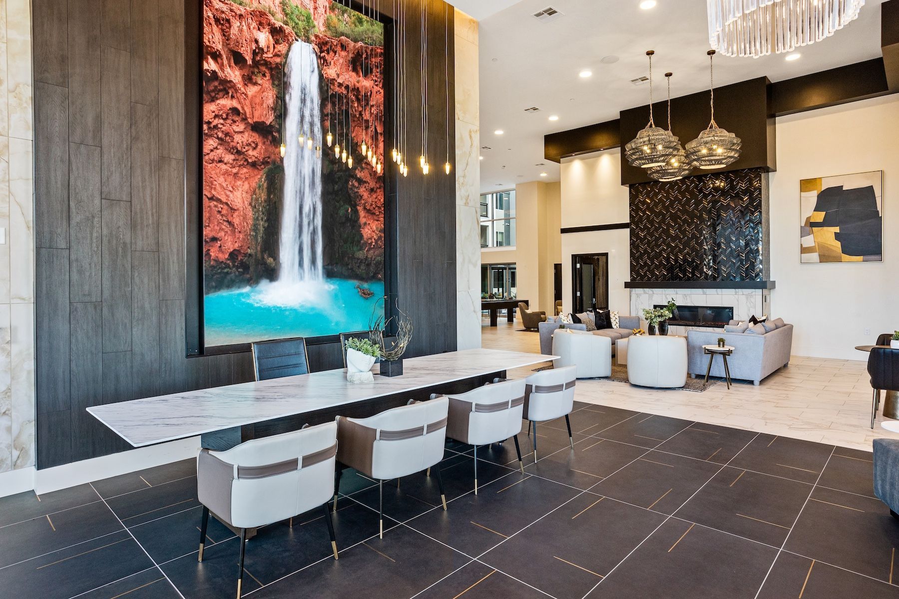 Lobby with a large waterfall art piece, long marble table with chairs, and seating area with fireplace at Echo Biltmore in Phoenix, AZ..