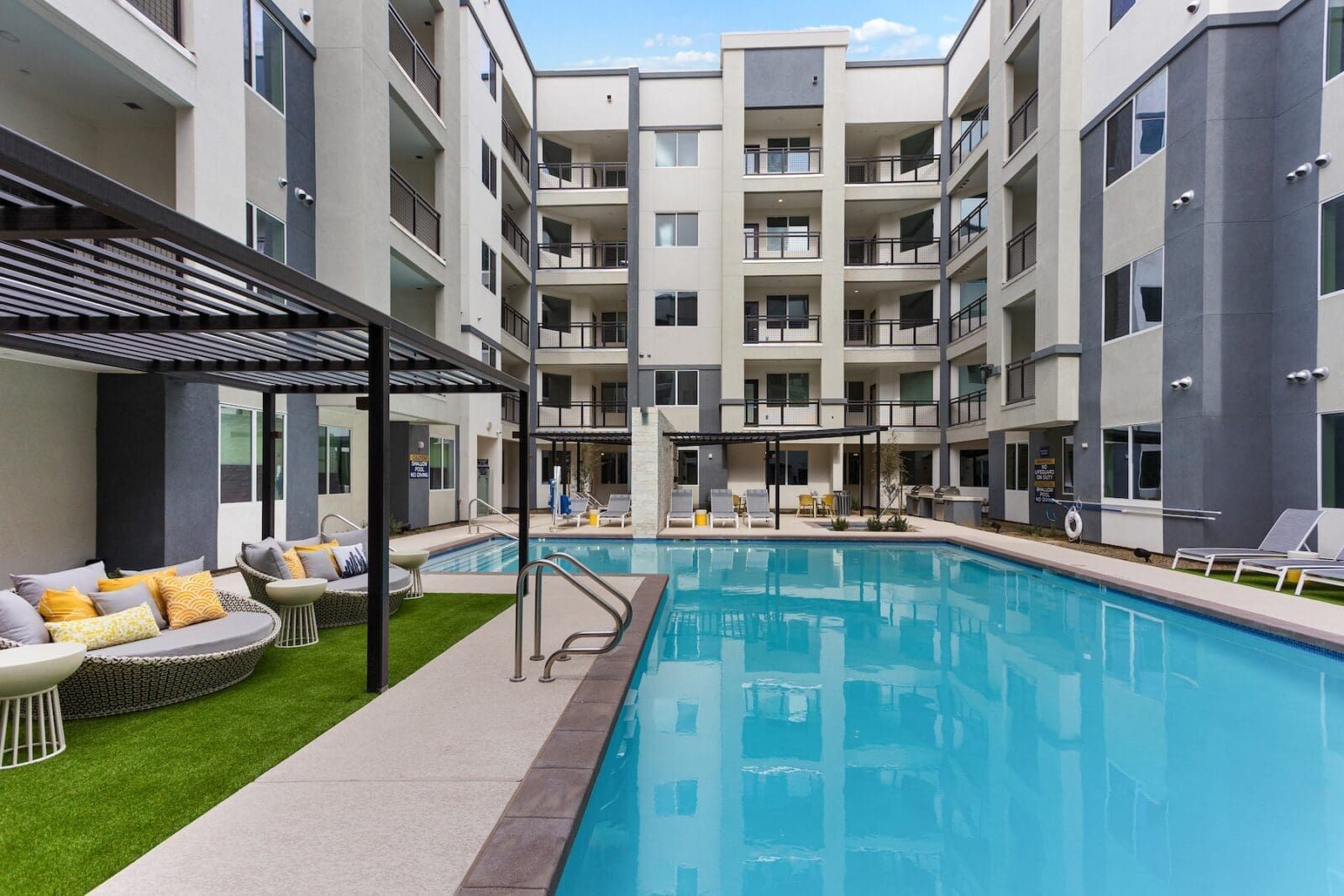 Courtyard with pool, lounge furniture, and balconies in a modern apartment complex at Echo Biltmore in Phoenix, AZ..