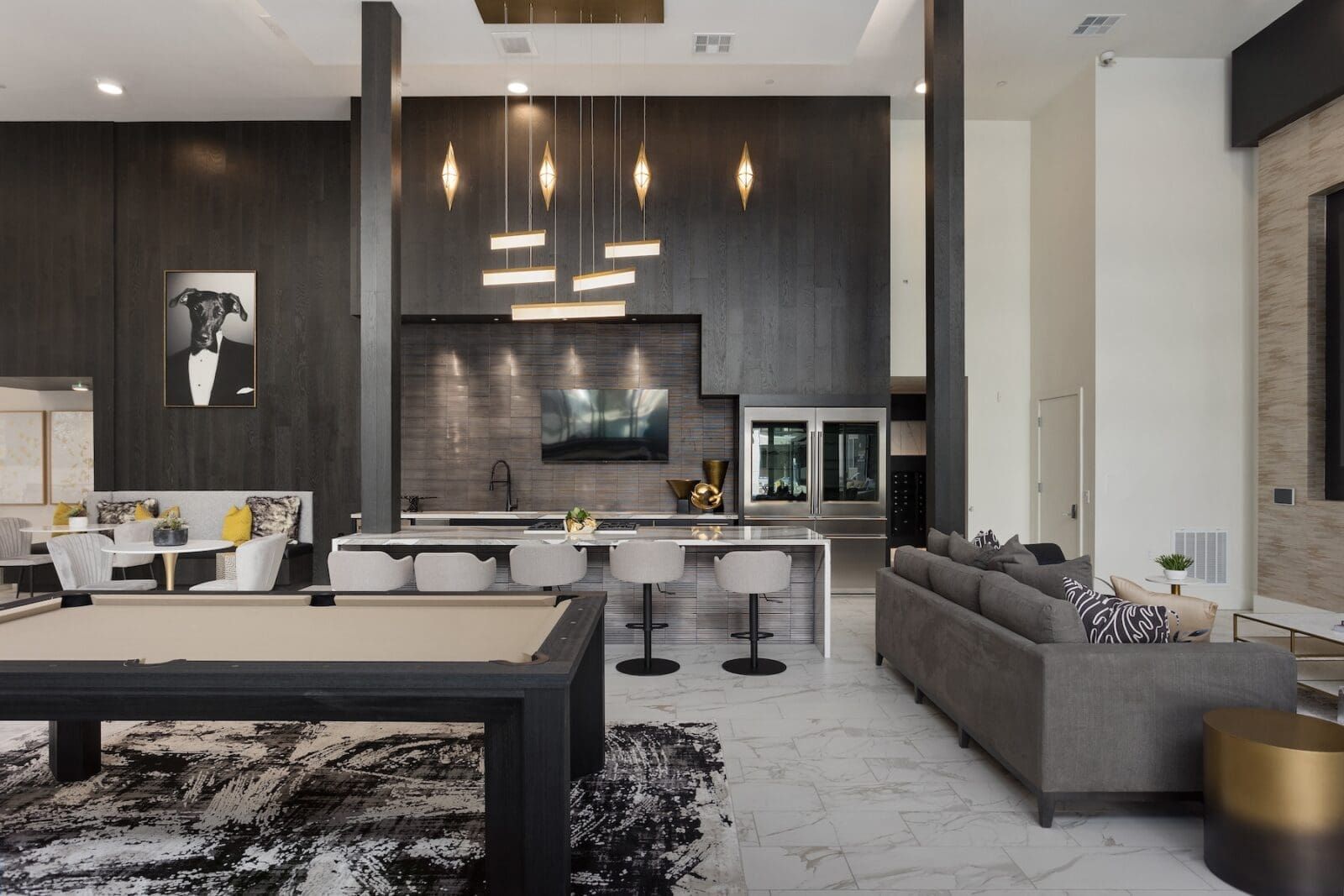 Modern apartment lounge with a pool table, kitchen island, and seating at Echo Biltmore in Phoenix, AZ..