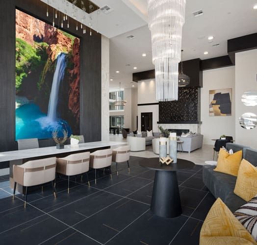 Lobby with waterfall mural, seating, and a large chandelier. Black tiled floor and modern decor at Echo Biltmore in Phoenix, AZ..