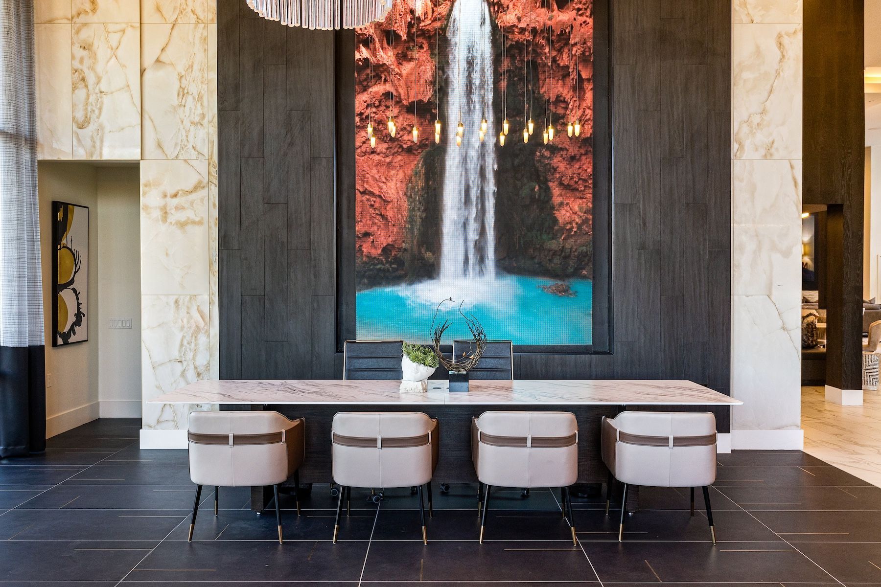 Long table with chairs in front of a large waterfall painting in a modern lobby at Echo Biltmore in Phoenix, AZ..
