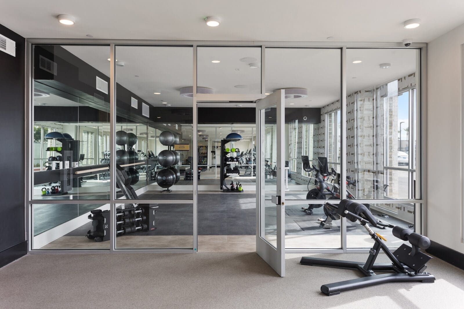 Gym interior with glass walls, weights, and exercise equipment at Echo Biltmore in Phoenix, AZ..